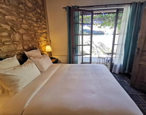 圣雷米普罗旺斯Hôtel Sous les Figuiers - Piscine, parking, centre ville的卧室配有一张白色大床和滑动玻璃门
