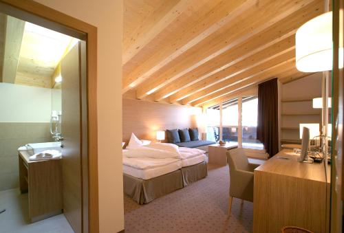 圣安东阿尔贝格Quality Hosts Arlberg - Hotel Goldenes Kreuz B&B的配有一张床和一张书桌的酒店客房