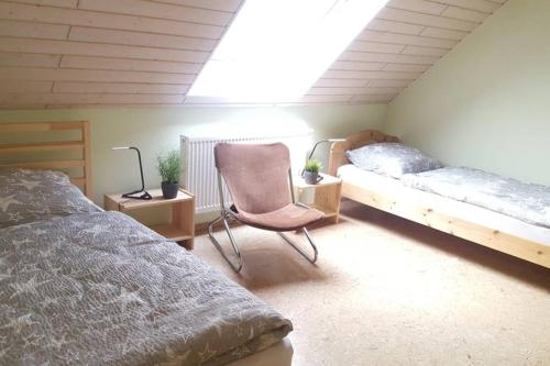 Ober-AbtsteinachAnna - neue Ferienwohnung mit Blick ins Grüne的一间卧室配有两张床、椅子和一盏灯。