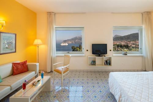 索伦托布里斯托尔酒店的酒店客房设有床、沙发和2个窗户。
