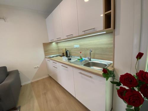 莫斯塔尔Apartments & Rooms Mostar Story的厨房配有白色橱柜、水槽和红色玫瑰