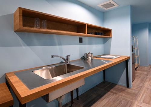 宫古岛HOTEL PINK HIBISCUS的厨房配有不锈钢水槽和木台面