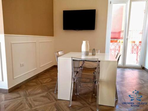 曼弗雷多尼亚B&B Orchidea Celeste的客厅配有桌子和墙上的电视