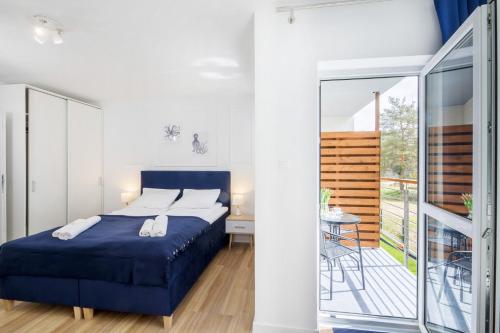 波德贝Apartament 12B Blue Marine Poddąbie的一间卧室设有蓝色的床和一个阳台