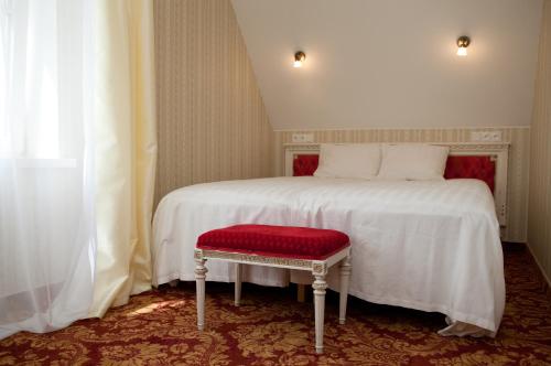 Rõuge奥比库洛别墅的卧室配有一张白色床和红色座椅。