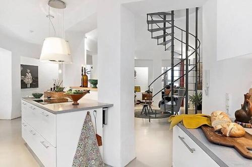 斯塔德Ystads Gamla Vattentorn的一间白色的厨房,在房间内设有一个螺旋楼梯
