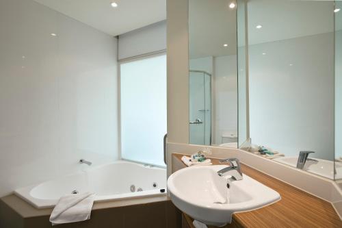 卡尔斯The Waves Apartments的一间带水槽、浴缸和镜子的浴室