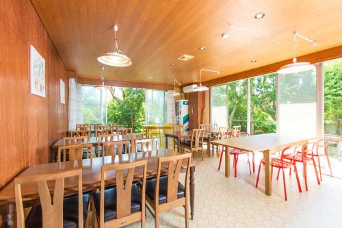 锯南町保田日落微风酒店的餐厅设有木桌、椅子和窗户。