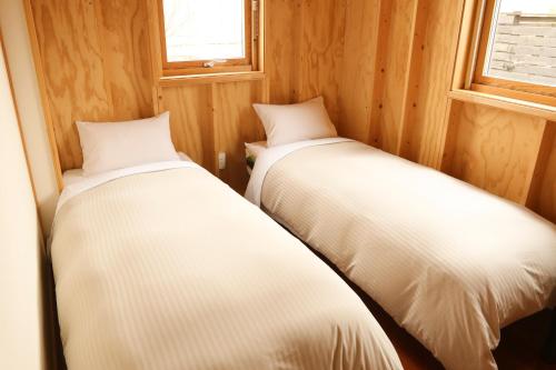 美瑛町福托格美瑛旅馆的小型客房的两张床,设有木墙