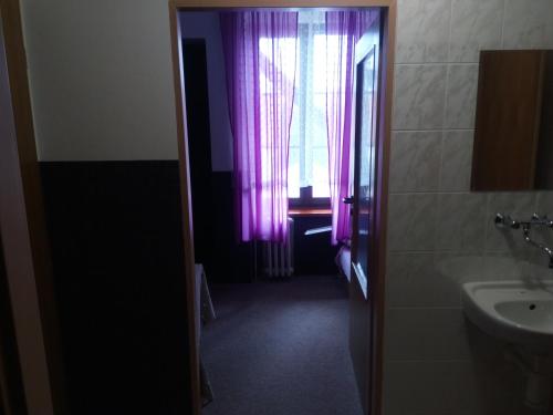克拉托维波普尔达膳食公寓的一间带水槽的浴室和一个带紫色窗帘的窗户