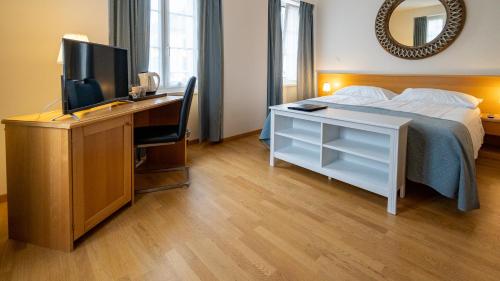 布勒Hôtel du Cheval Blanc - City center的一间卧室配有一张床和一张书桌及电视