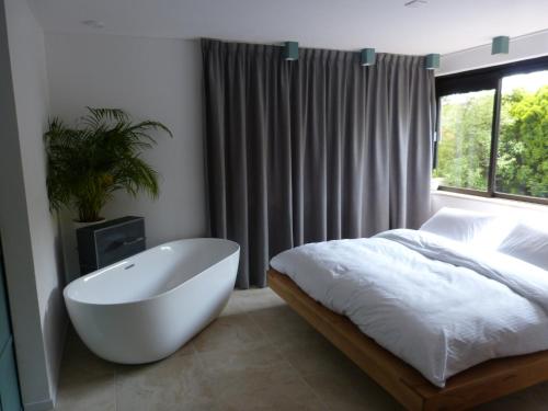 NoordwoldeHuize Triangel - Wellness studio met sauna的卧室配有白色浴缸、床和窗户。