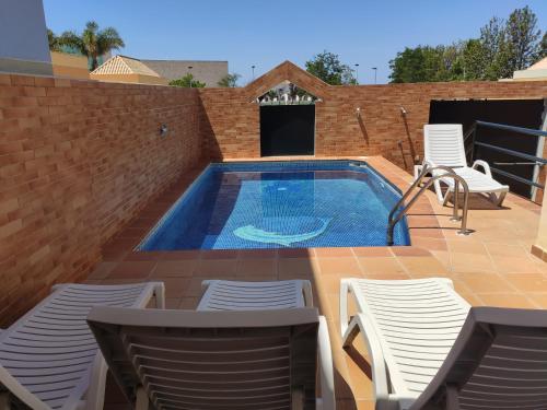 法鲁Casa das Figuras的庭院内的游泳池配有桌椅