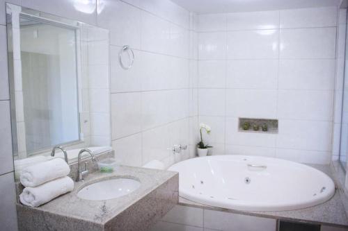 CeilândiaHOTEL VINTE UM的白色的浴室设有浴缸和水槽。