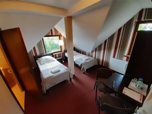 兹盖日Route One - Restauracja & Pokoje Hotelowe的酒店客房带两张床和一张桌子以及椅子。