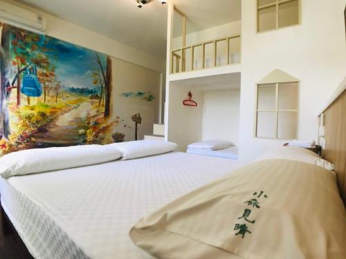 花莲市小森见晴背包客民宿的一间卧室设有两张床,墙上挂着一幅画