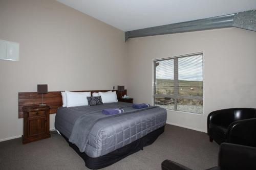 WaipiataTussock Lodge - Waipiata的卧室配有床、椅子和窗户。