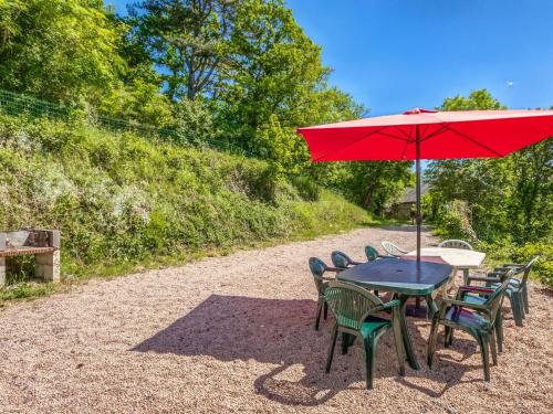 蓬特吉博Lovely Cottage in Pontgibaud with Garden near Lake的一张桌子和椅子,配有红色雨伞