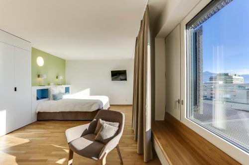 洛桑患者酒店的一间卧室设有一张床和一个大窗户