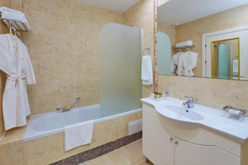 阳光海滩Planeta Hotel & Aquapark - Ultra All Inclusive的带浴缸、水槽和镜子的浴室