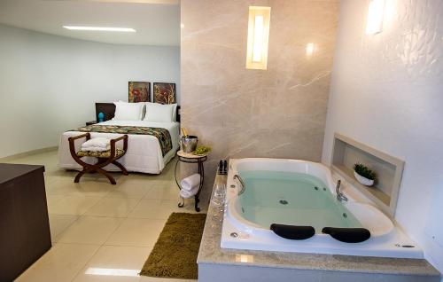 因佩拉特里斯Residence Hotel Imperatriz的一间带浴缸的浴室(位于床前)