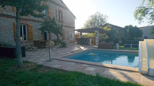 AlbiasLa Ferme aux portes de Montauban - Avec piscine的一座游泳池,位于一座建筑旁的院子内