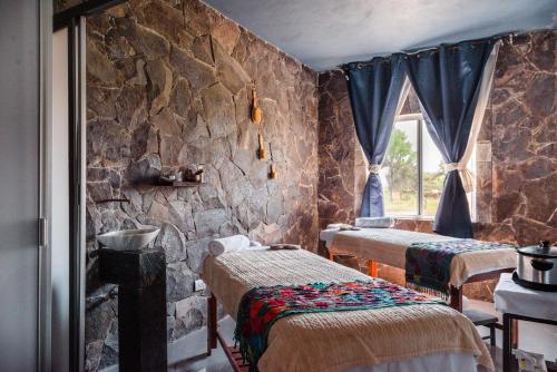 AtotonilcoLila Hotel的一间设有三张床和石墙的房间