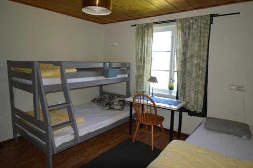 ÖverhörnäsHögsnäsgården的一间卧室配有双层床、一张桌子和一张床。