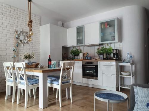 波别罗沃Apartament Bursztyn的厨房配有白色橱柜和桌椅