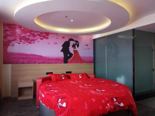 尚客优酒店山东济南济阳县英才学院北校区店的卧室配有红色的床,墙上挂有绘画作品
