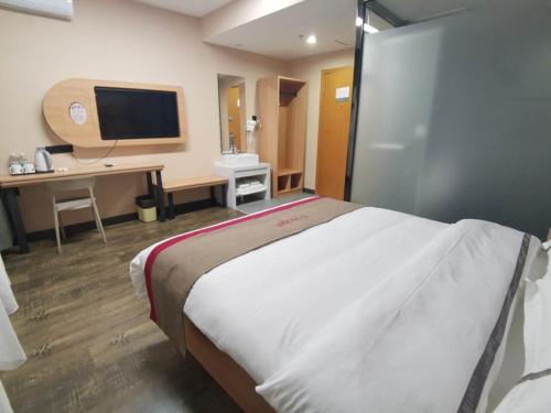 呼和浩特尚客优酒店内蒙古呼和浩特新城区新华广场店的一间卧室配有一张床、一张书桌和一台电视