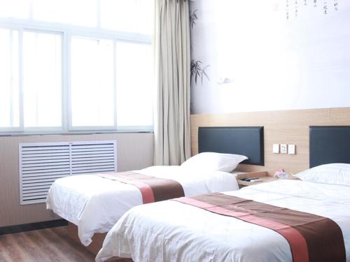 廊坊骏怡连锁河北廊坊广阳区廊坊站店的酒店客房设有两张床和窗户。