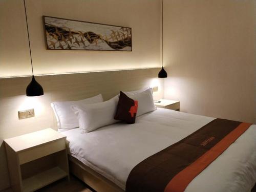 兰州骏怡连锁甘肃兰州城关区兰州大学店的一间卧室配有一张带两盏灯的大型白色床。