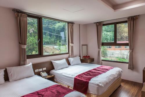 鹿谷乡新景宏渡假村的带2扇窗户的客房内的2张床