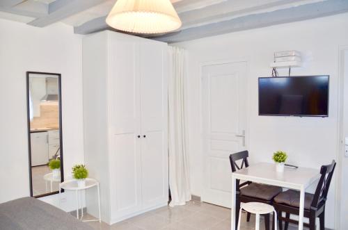 希农Mon petit chez moi的客厅配有桌子,墙上配有电视