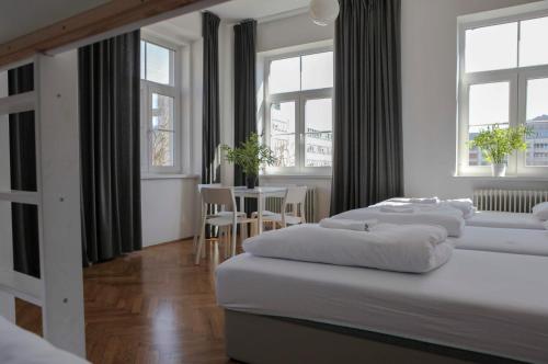 卢布尔雅那朋克特C旅舍的一间卧室设有三张床、一张桌子和窗户。
