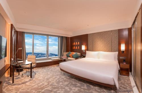 澳门澳门皇冠假日酒店的卧室配有一张白色大床和一张书桌