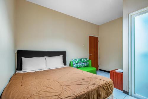 三宝垄Griya Stadion的一间卧室配有一张床和一把绿色椅子