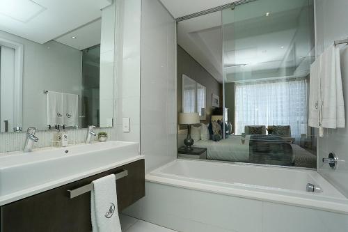 约翰内斯堡304 Sandton Skye的白色的浴室设有浴缸和大镜子