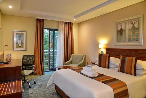 约翰内斯堡City Lodge Hotel Fourways的酒店客房配有两张床和一张书桌