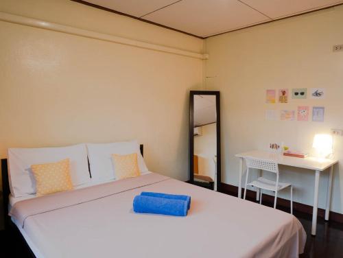 曼谷陈查拉99旅馆的一间卧室配有一张床、一张书桌和一面镜子