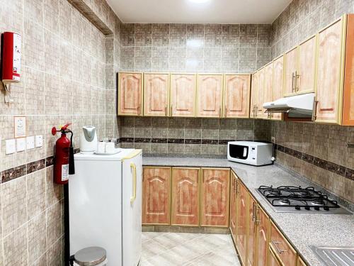 马斯喀特Al Murooj Hotel Apartments的厨房配有白色冰箱和木制橱柜。