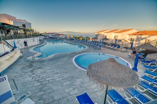 圣地亚哥港奥纳拉斯罗萨斯公寓式酒店的一个带蓝色椅子和遮阳伞的大型游泳池