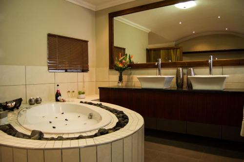 温特和克APS Guesthouse的一间带大浴缸和大镜子的浴室