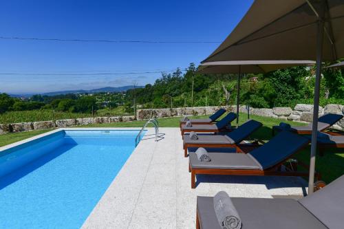 阿马兰特Vila Coura的一个带躺椅和遮阳伞的游泳池