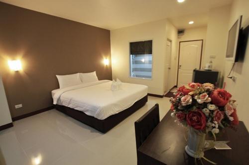 坤敬Panwalee Hotel的一间酒店客房,配有床和鲜花