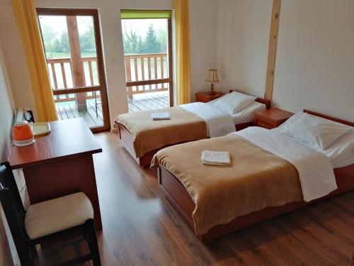 CieszkówRestauracja Teo的酒店客房设有两张床、一张桌子和一张书桌。