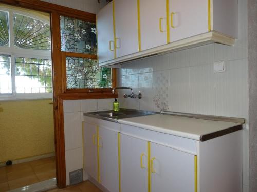 拉马丽娜Casa Mediterráneo的厨房配有白色橱柜、水槽和窗户。