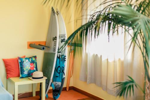 佩尼契Peniche Beach House的一间设有两个冲浪板、一张桌子和植物的房间