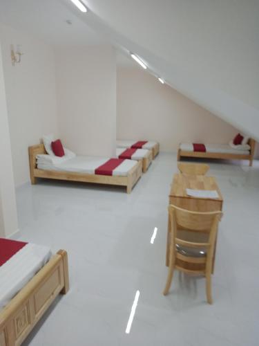 大叻Mango Hotel Dalat的一间设有两张床、一张桌子和一把椅子的房间